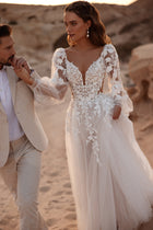 Alia’s bridal dress has a fitted lace corset bodice with 3D floral appliqués and a plunging V neckline, elegantly defining the waist.