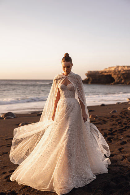 In motion, Amira’s hooded cape drifts softly and the train lifts beautifully – accentuating the dress’s airy elegance.