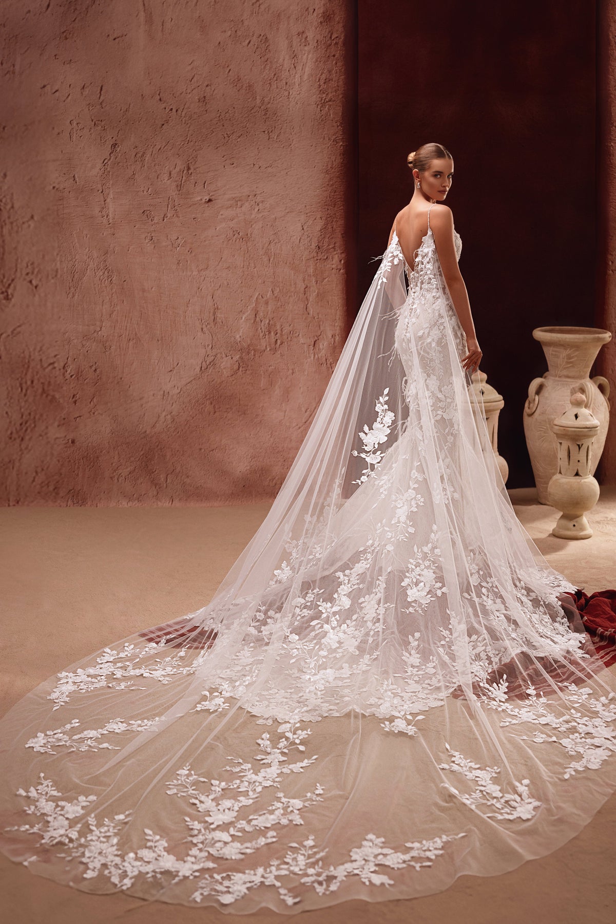 Aspasia bridal cape with 3D floral appliqués, crafted from soft tulle, adds a dramatic and romantic touch to the wedding dress.