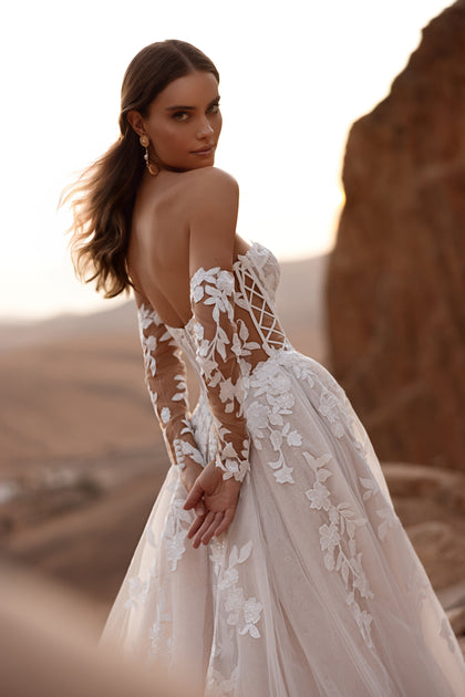 The Nabila princess wedding dress features an off-the-shoulder neckline and a flowing tulle train, creating a breathtaking bridal look.
