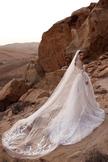 The Nabila wedding dress with lace sleeves and a structured corset bodice highlights a romantic yet modern bridal style.