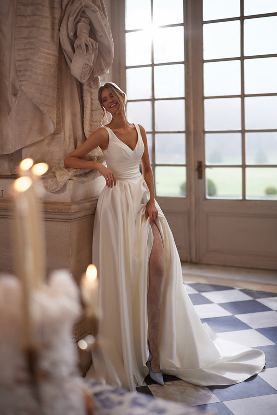 Elvira wedding dress – A-line bridal gown with an open V-neckline and clean draped skirt with a high slit.
