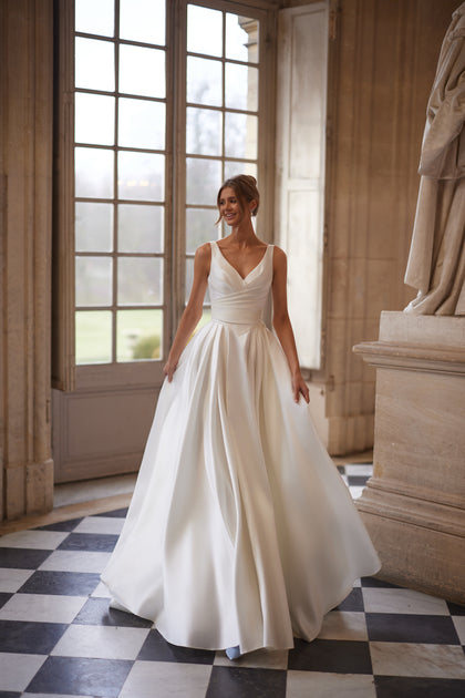 Elvira wedding dress – an open V-neckline and clean draped skirt with a high slit.