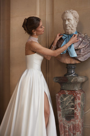Lucienne wedding dress – a crystal-embellished illusion neckline and draped satin skirt with a high slit.