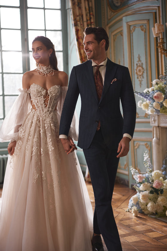 Bride and groom indoors, with Melusine A-line wedding dress in floral lace and a lace choker