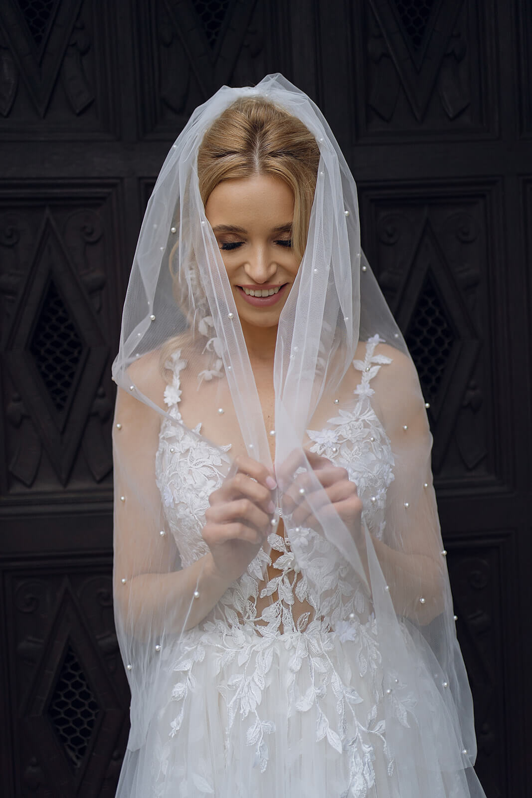 Regular pearl veil brought forward, tulle falling over the arms above a lace bodice