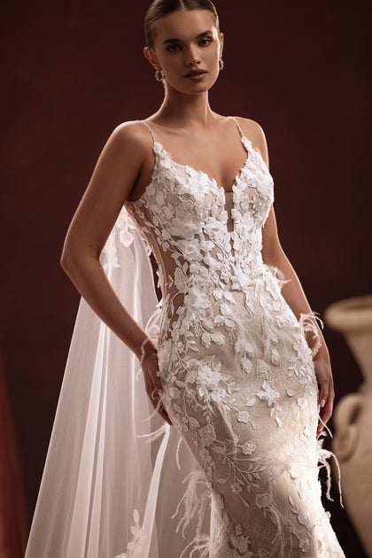 The Aspasia wedding gown with a dramatic lace train and floral-embroidered cape creates an unforgettable bridal silhouette.