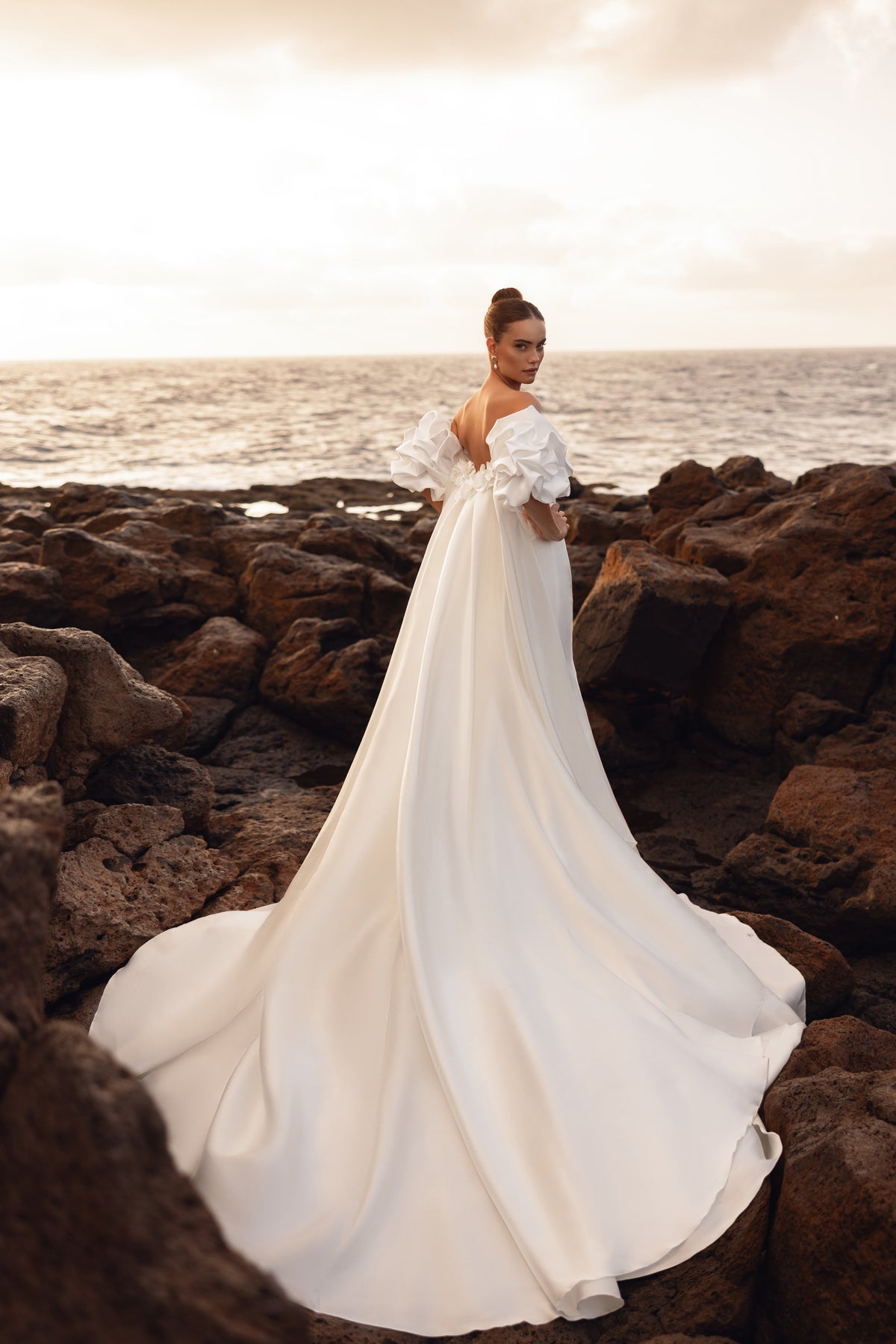 Backless wedding gown with an extra-long train, designed for dramatic seaside bridal portraits.