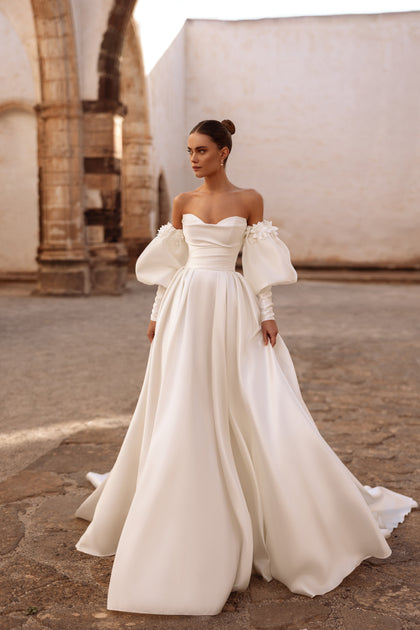Elegant off-shoulder satin wedding dress Anika with puff sleeves and floral appliqués for a romantic bridal look.