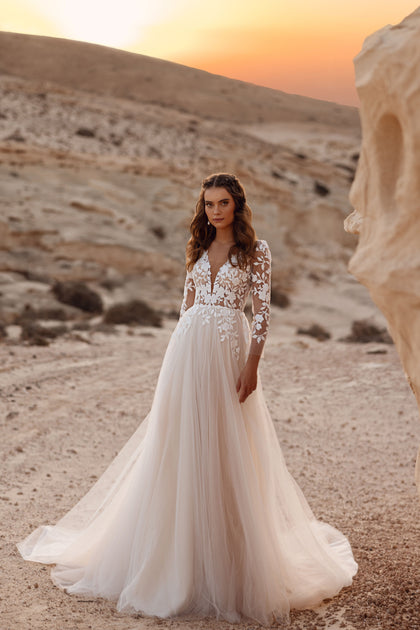 The Armori wedding gown features a deep V neckline and 3/4 lace sleeves, creating a timeless romantic bridal look.