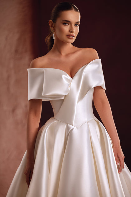 Close-up of the Avin wedding dress shows the luxurious satin sheen and sculptural off-shoulder neckline.