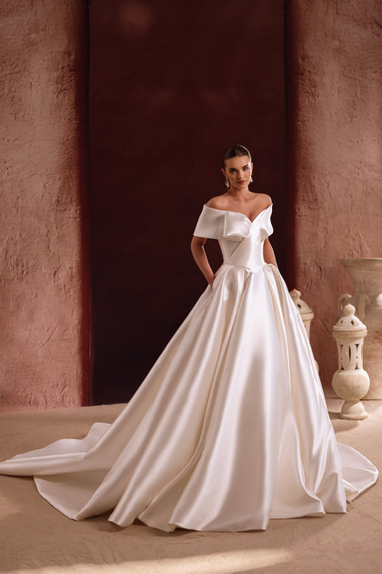 The Avin wedding dress with an off-the-shoulder satin bodice showcases a sculptural design and modern elegance.