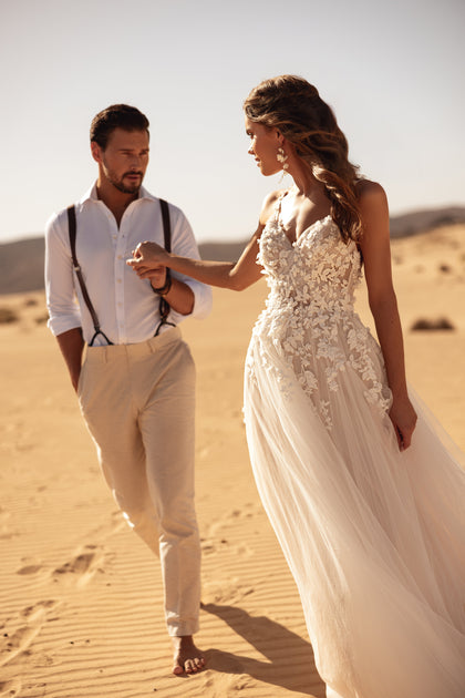 The Aviva wedding gown with a floral lace bodice and high slit reflects modern bridal fashion with romantic details.