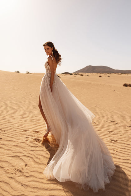 The Aviva wedding gown with a flowing tulle skirt and front slit adds effortless movement and grace to the bridal look.