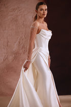 The Aylin wedding dress features pearl-embellished sheer sleeves and a draped satin neckline for a timeless bridal look.