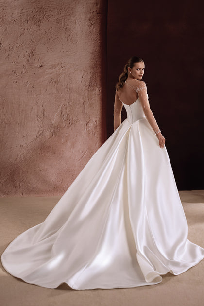 The Aylin satin wedding gown features a button-down back design, enhancing the bride’s figure with refined charm.