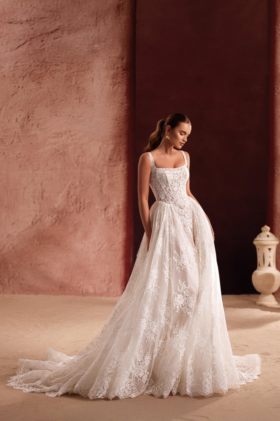 The Becco wedding dress features a lace corset bodice with a lace-up back, blending classic bridal elegance with romantic charm.
