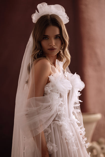 The Bella wedding gown with a thigh-high slit and floral appliqués combines sensual elegance with airy romance.