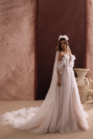 The back of the Bella wedding gown reveals a sweeping tulle train adorned with 3D flowers for a fairytale bridal look.