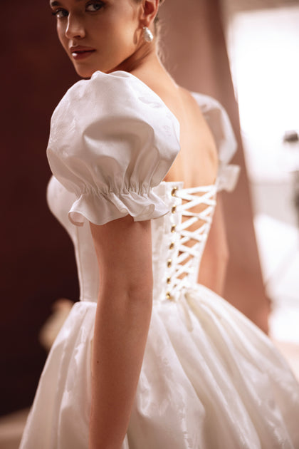 The Daphne short wedding gown with sweetheart neckline and puff sleeves radiates modern charm and feminine grace.