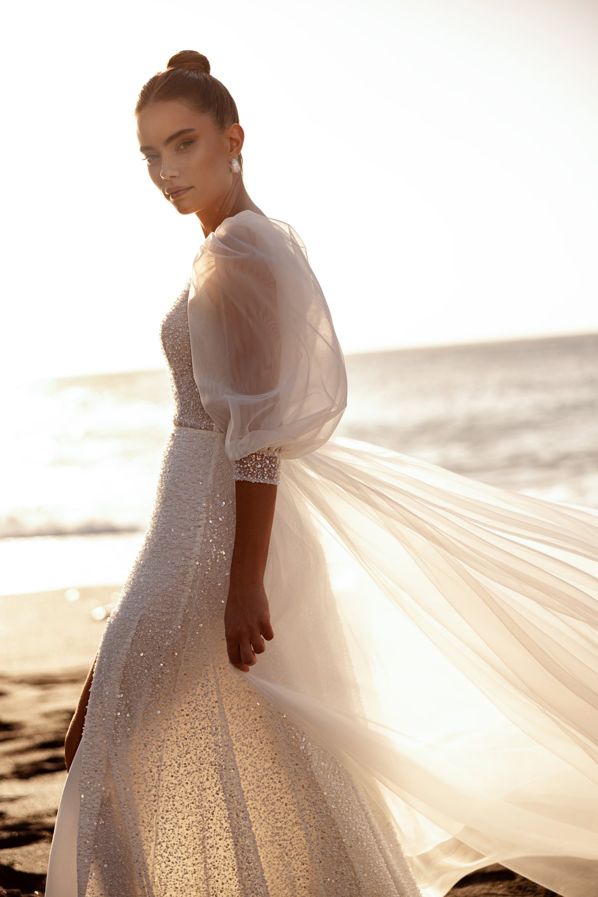 The Davina wedding gown with glittering texture and voluminous sleeves highlights feminine beauty with a touch of glamour.