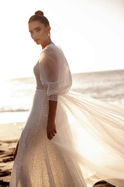 The Davina wedding gown with glittering texture and voluminous sleeves highlights feminine beauty with a touch of glamour.