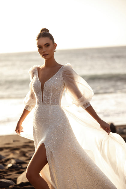 The Davina wedding gown with sheer puff sleeves and sparkling details exudes elegance and lightness in the sunlight.