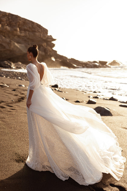 The Davina wedding dress showcases a dramatic tulle train and open back, creating a romantic and airy bridal silhouette.