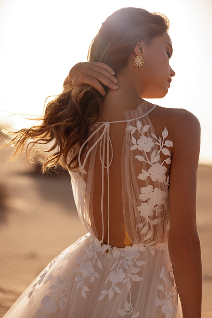 The Ellie wedding dress glows in desert light, featuring a sheer floral lace bodice and flowing tulle skirt.