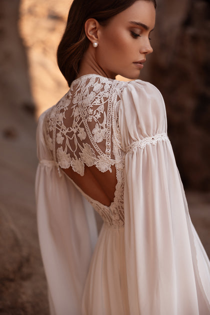 The Etra wedding gown features a stunning lace back and flowing train, designed for brides seeking effortless elegance.