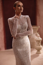 The Henriette fitted lace wedding gown highlights the bride’s figure with intricate beading and a sophisticated high neckline.