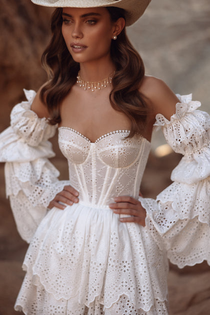 The Jolena short wedding dress in western boho style combines a lace corset with a playful embroidered skirt for a bold bridal look.