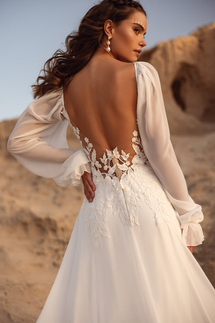 The Judith wedding gown with a sheer lace bodice and billowy sleeves combines boho spirit with refined elegance.