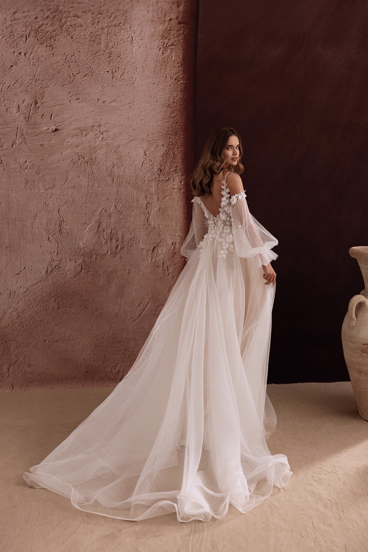 Side view of Lilibeth wedding dress among amphorae, with a soft tulle skirt and train