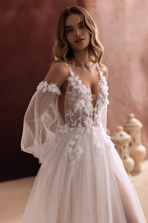 Lilibeth wedding dress with plunging neckline and romantic tulle puff sleeves tied with bows highlights feminine elegance.