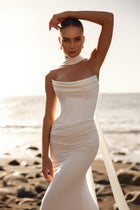 The Luna wedding dress features a sleek fitted silhouette with a dramatic train, perfect for a modern beach wedding.