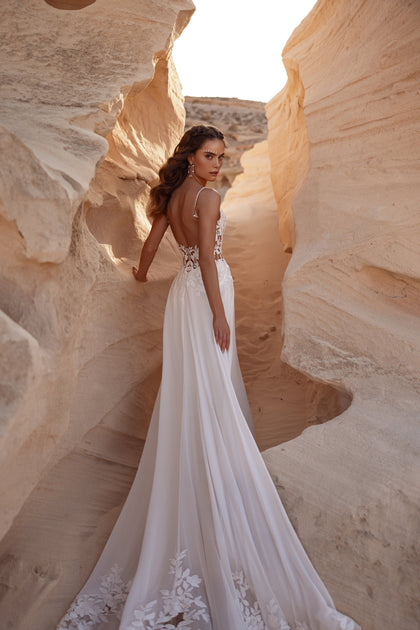 The Malika wedding dress with an open back and soft A-line skirt blends boho romance with modern simplicity.
