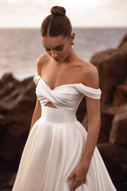 Mellisandre off-the-shoulder bridal corset dress with a draped neckline, blending modern style with timeless romance.