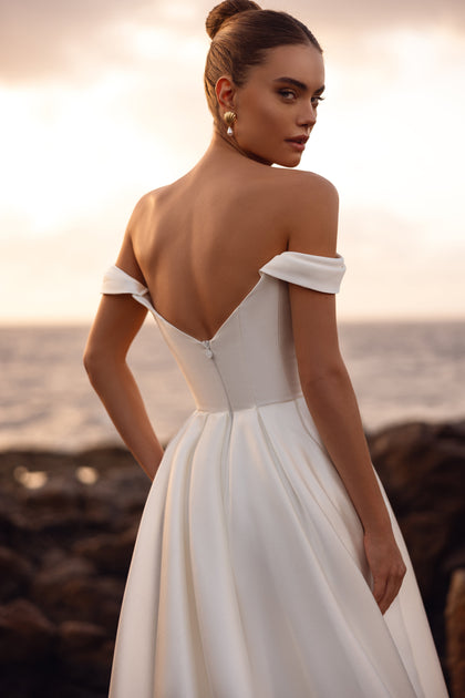 Mellisandre wedding dress featuring an off-the-shoulder neckline and deep open back, perfect for timeless bridal elegance.