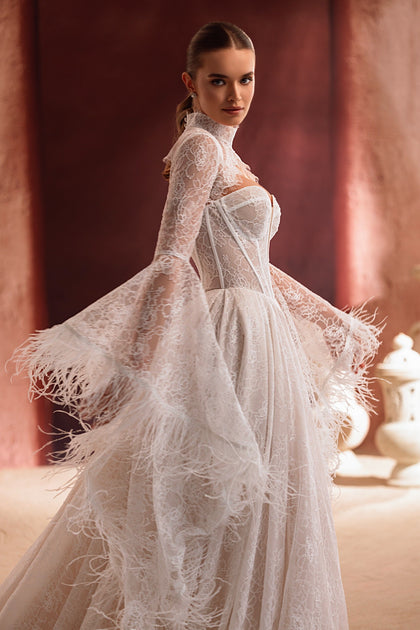 The Michelle wedding gown with dramatic bell sleeves and feather accents offers a bold, couture-inspired bridal style.