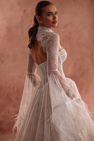 The Michelle lace wedding dress with feather-trimmed sleeves and a corset bodice captures a boho-luxury bridal look.