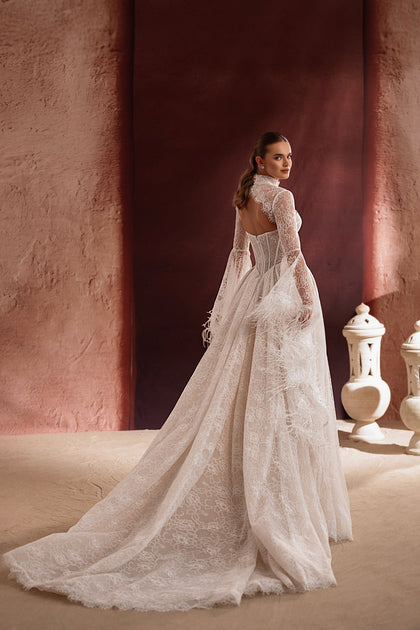 The Michelle wedding gown with a lace high neck, long train, and feather details creates a show-stopping couture bridal look.