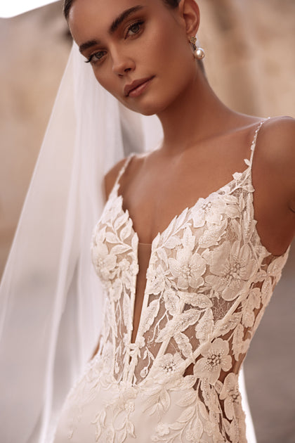 The Munira lace wedding dress features 3D floral appliqués and sheer panels that highlight a modern yet romantic bridal look.