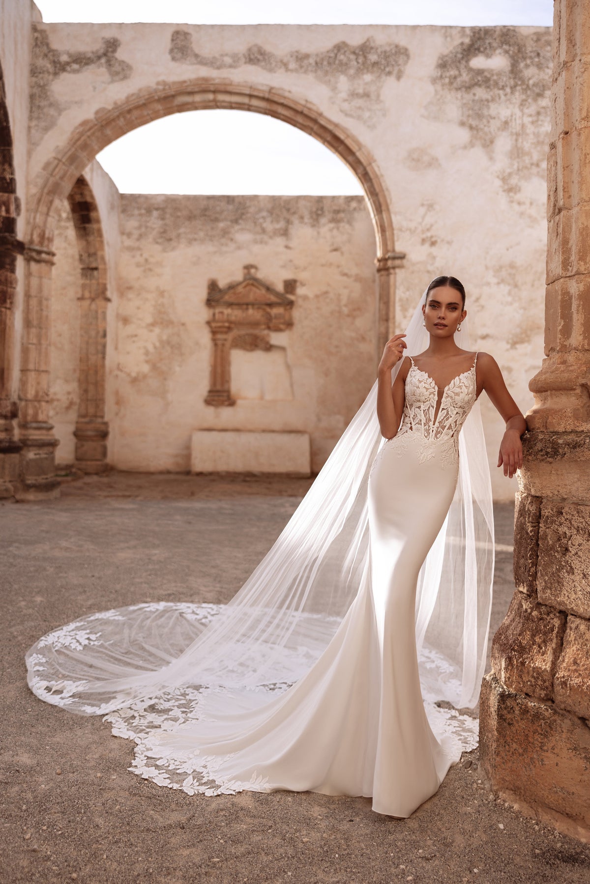 Front view of Cathedral veil Munira falling beside a satin mermaid wedding dress