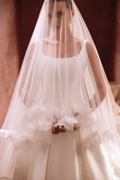 The Nicolette wedding dress paired with a floral-appliqué veil delivers a soft, romantic bridal look.
