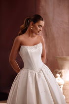 The Noor satin ball gown wedding dress with a strapless corset and pearl embellishments exudes timeless bridal elegance.