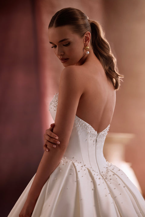 The Noor satin wedding dress with a dramatic full skirt and train showcases luxurious shine and couture-inspired design.