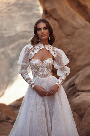 The Oasis lace wedding dress with puff sleeves and sheer tulle skirt blends vintage romance with couture-inspired elegance.