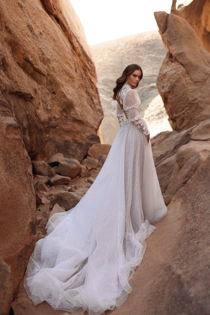 The Oasis wedding gown with a high neckline and lace long sleeves combines modern sophistication with timeless romance.