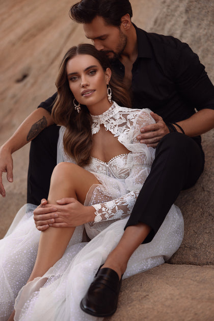 The Oasis wedding dress with a flowing train and lace detailing captures ethereal beauty and feminine grace.